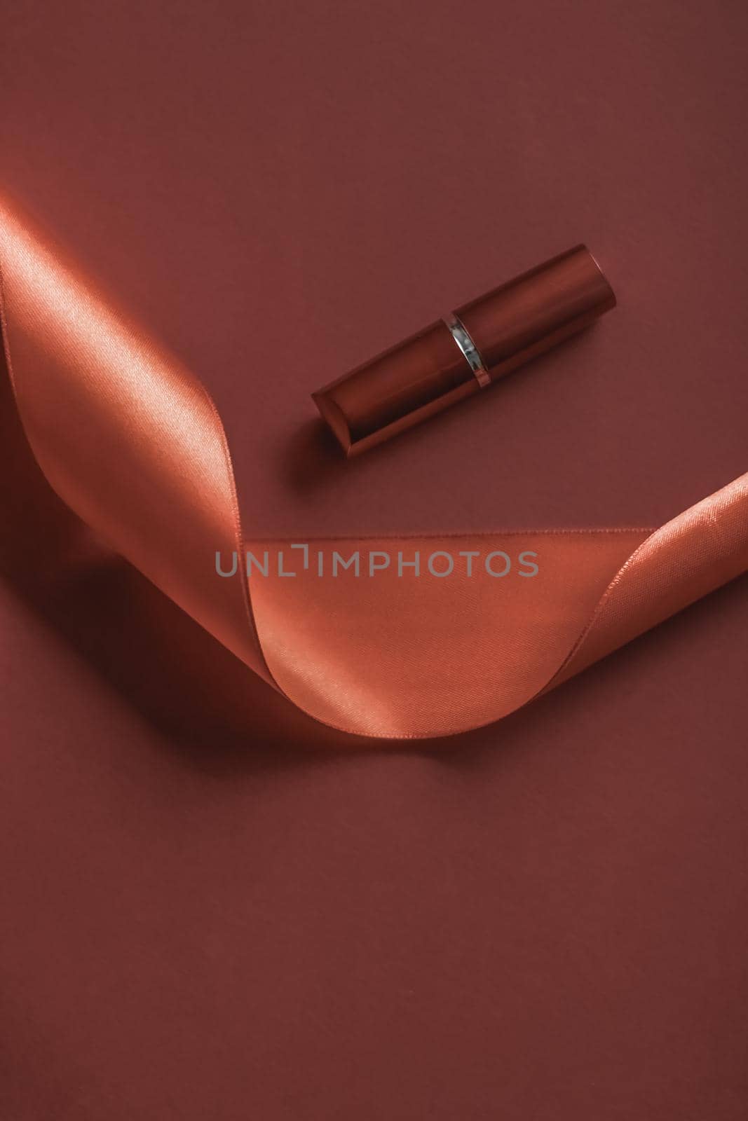 Cosmetic branding, glamour lip gloss and shopping sale concept - Luxury lipstick and silk ribbon on bronze holiday background, make-up and cosmetics flatlay for beauty brand product design