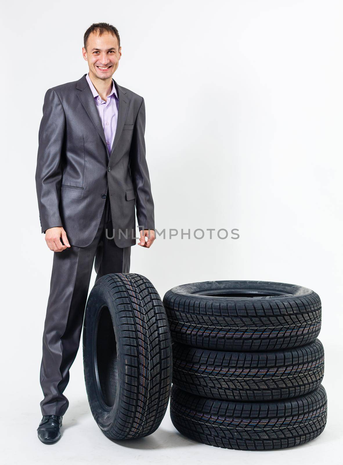 Car dealer man over tire tire background. Auto maintenance. by Andelov13