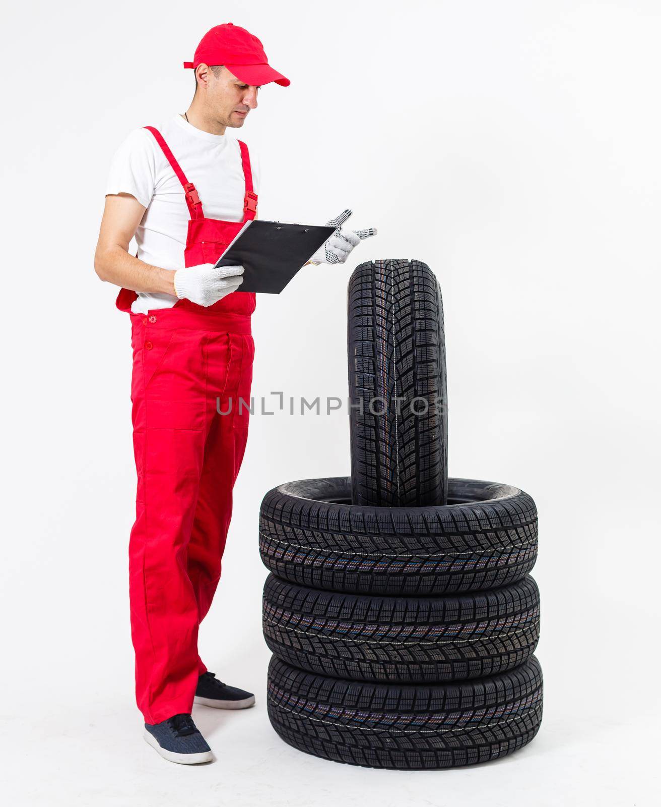 Mechanic holding a tire tire at the repair garage. replacement of winter and summer tires. by Andelov13