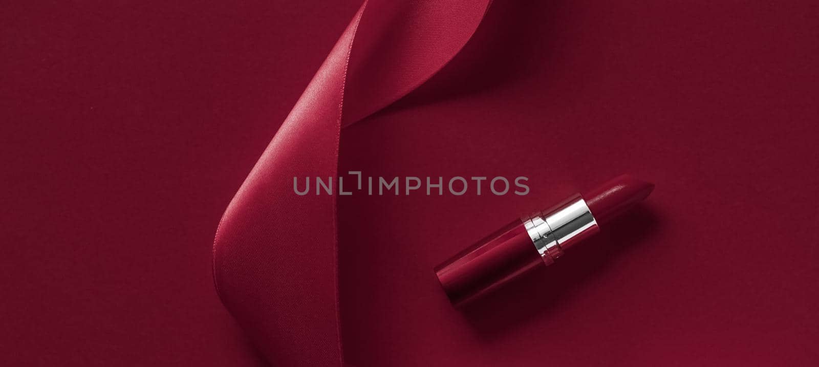 Luxury lipstick and silk ribbon on maroon holiday background, make-up and cosmetics flatlay for beauty brand product design by Anneleven