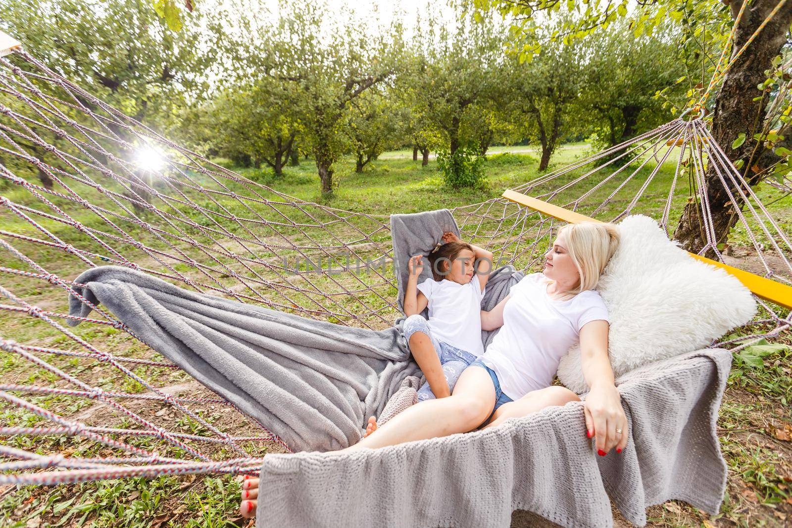 Mother And Daughter Sleeping In Garden Hammock Together by Andelov13