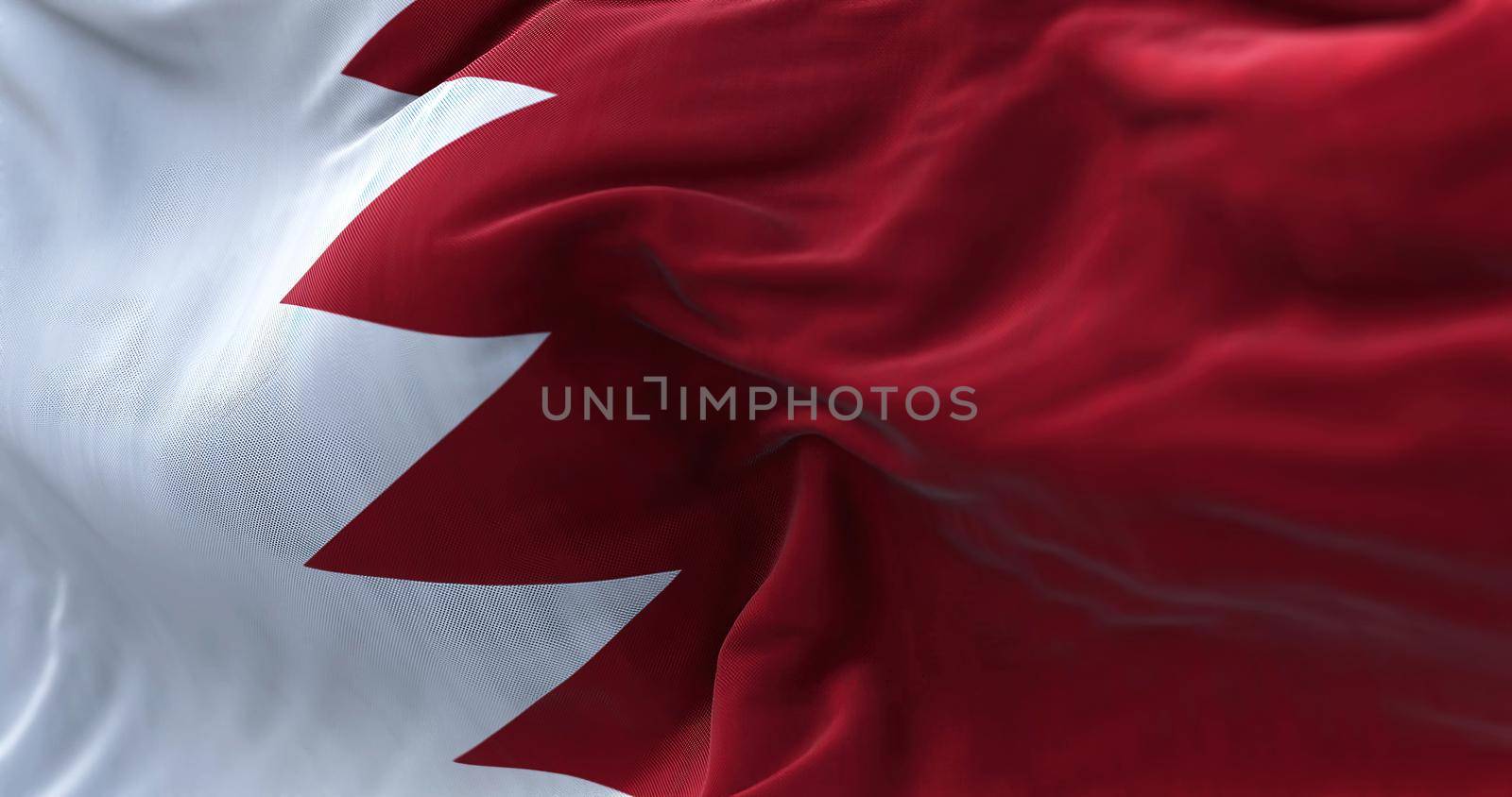 Close-up view of the Bahrain national flag waving in the wind. The Kingdom of Bahrain,[a] is an island country in Western Asia. Fabric textured background. Selective focus