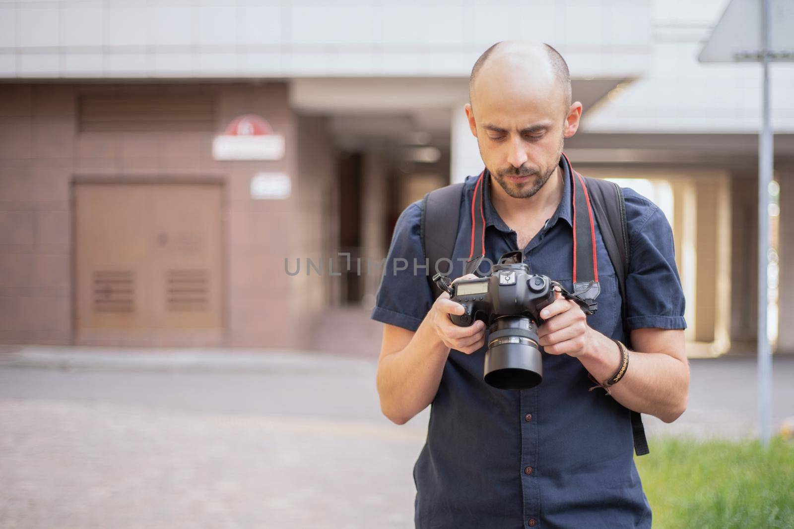 young man with a camera standing on a city street. by SmartPhotoLab