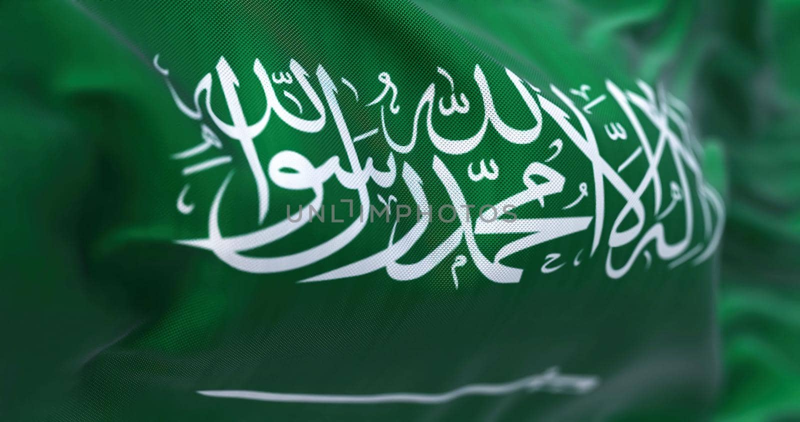 Close-up view of Saudi Arabia national flag waving in the wind. The Kingdom of Saudi Arabia (KSA) is a country on the Arabian Peninsula in Western Asia. Fabric textured background. Selective focus