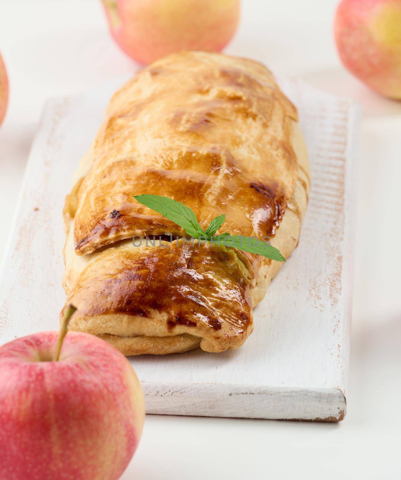 Baked strudel with apples on a white wooden board, delicious dessert