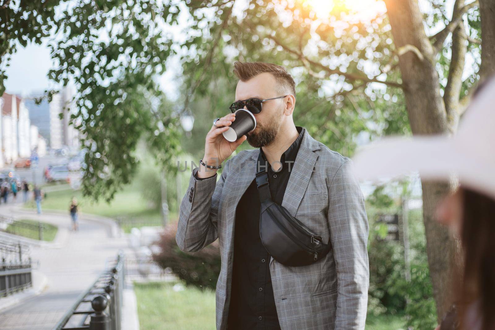 attractive male tourist with takeaway coffee standing on a city street.