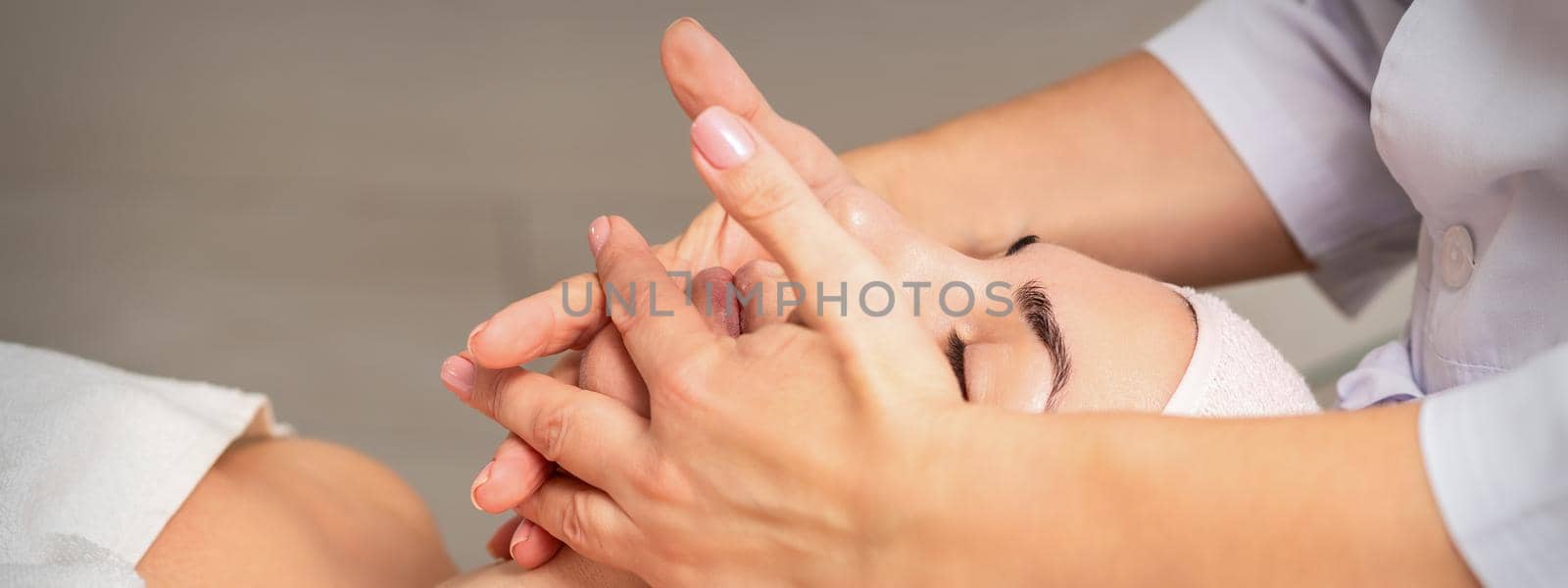 Beautiful caucasian young woman getting a facial massage at a beauty salon