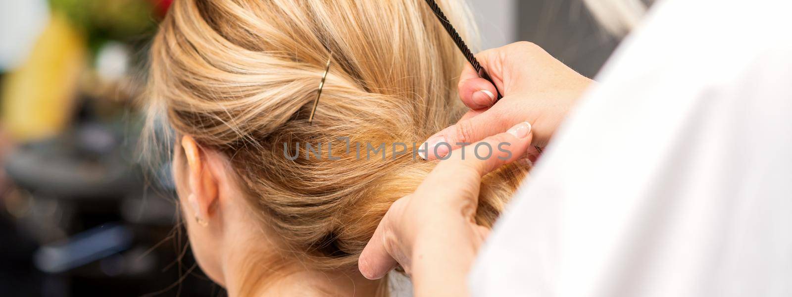 Close-up hairdresser styling blonde hair on the back of the head in a beauty salon. by okskukuruza