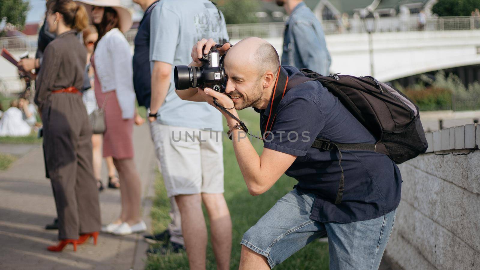 young man with a camera taking a photo during an excursion. by SmartPhotoLab