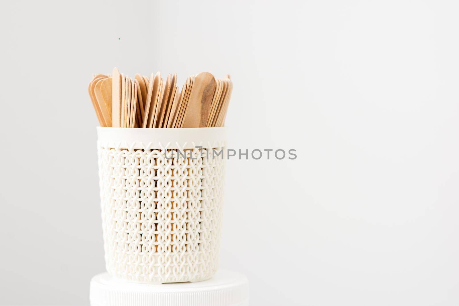 Sticks of wood for wax in white basket isolated on white background with copy space