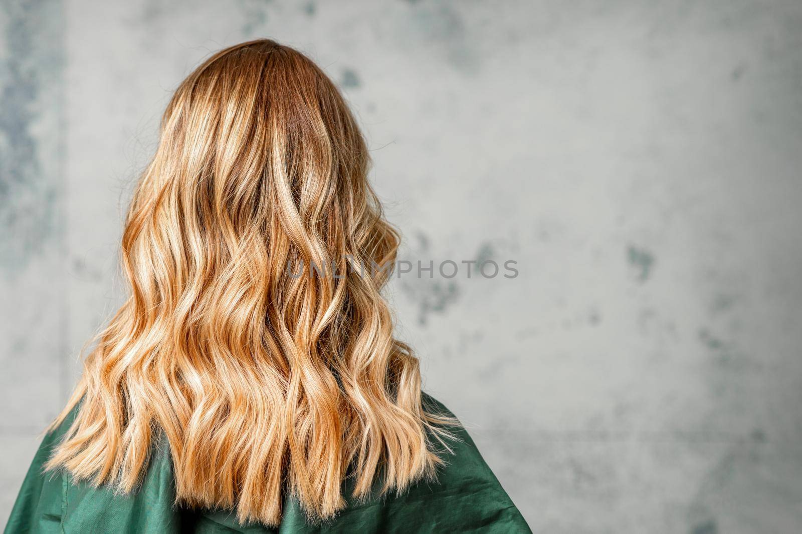 Rear View of a woman with long brown hair against a gray background