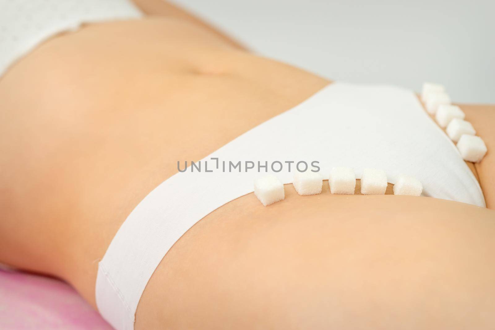 Sugar cubes lying in a row on female bikini zone, the concept of intimate depilation, problems of intimate hygiene