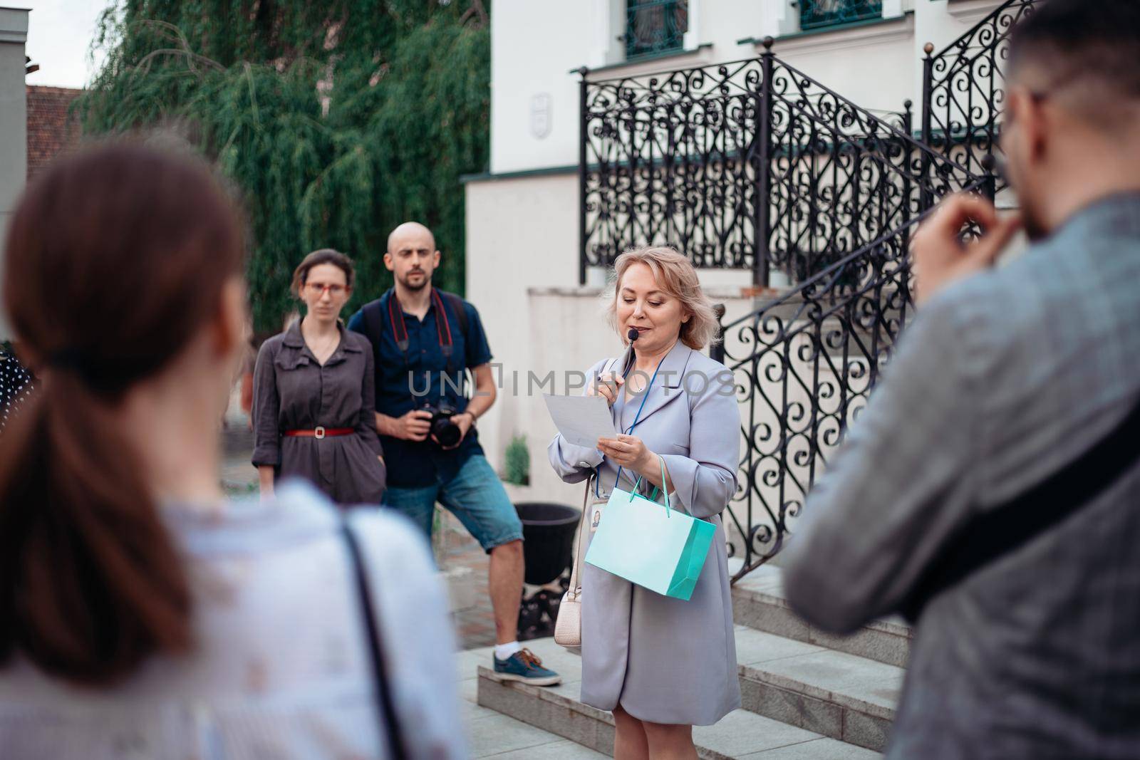 guide and a group of tourists standing on the steps of the hotel. by SmartPhotoLab