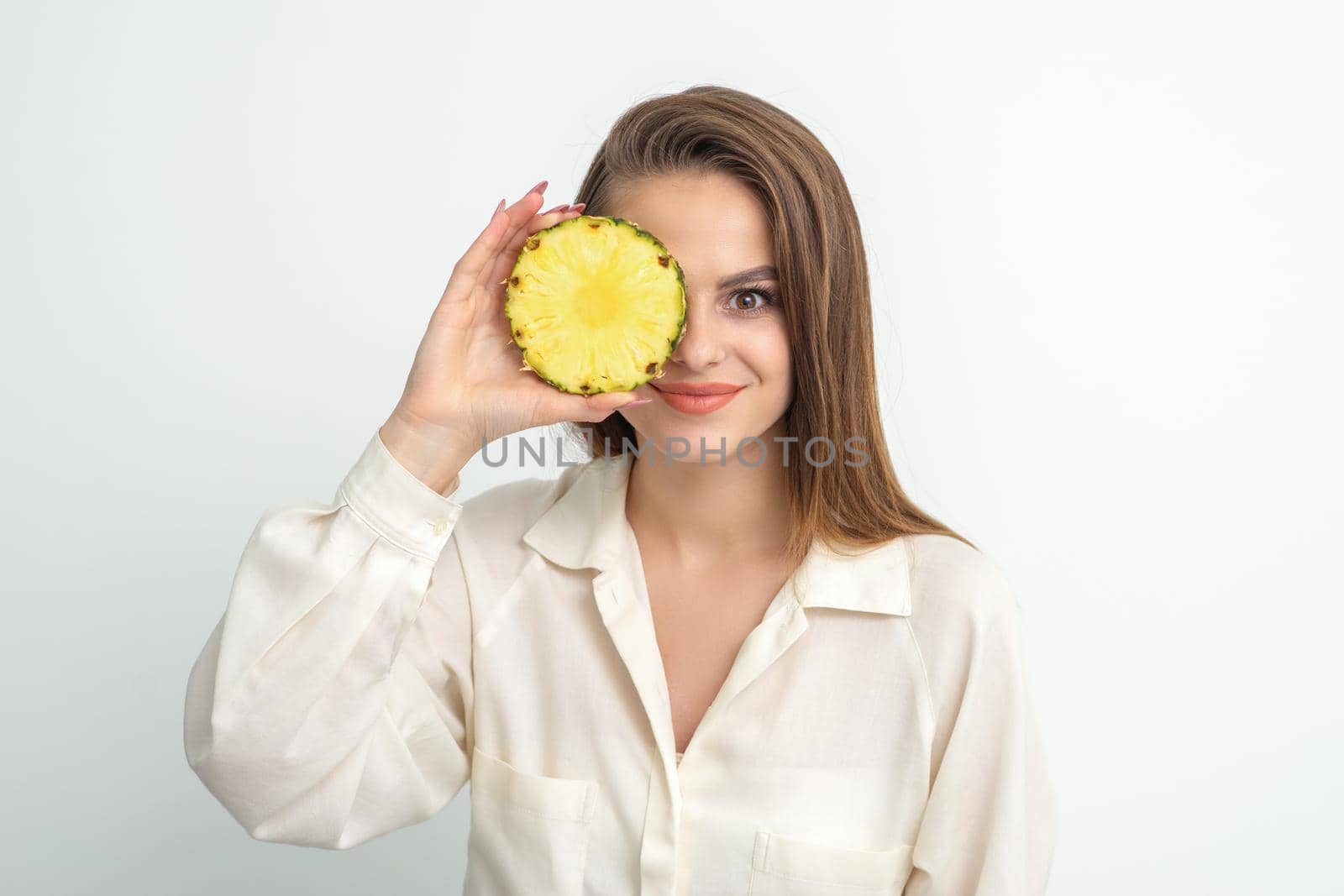 Attractive pretty nice young caucasian woman hold sliced pineapple covering her eye isolated on white color background