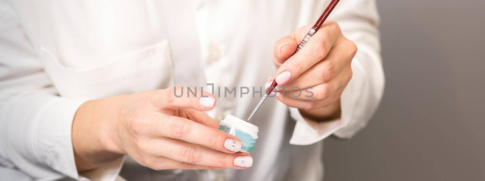 Blue glitter nail polish with a nail brush in hands of female manicurist. by okskukuruza