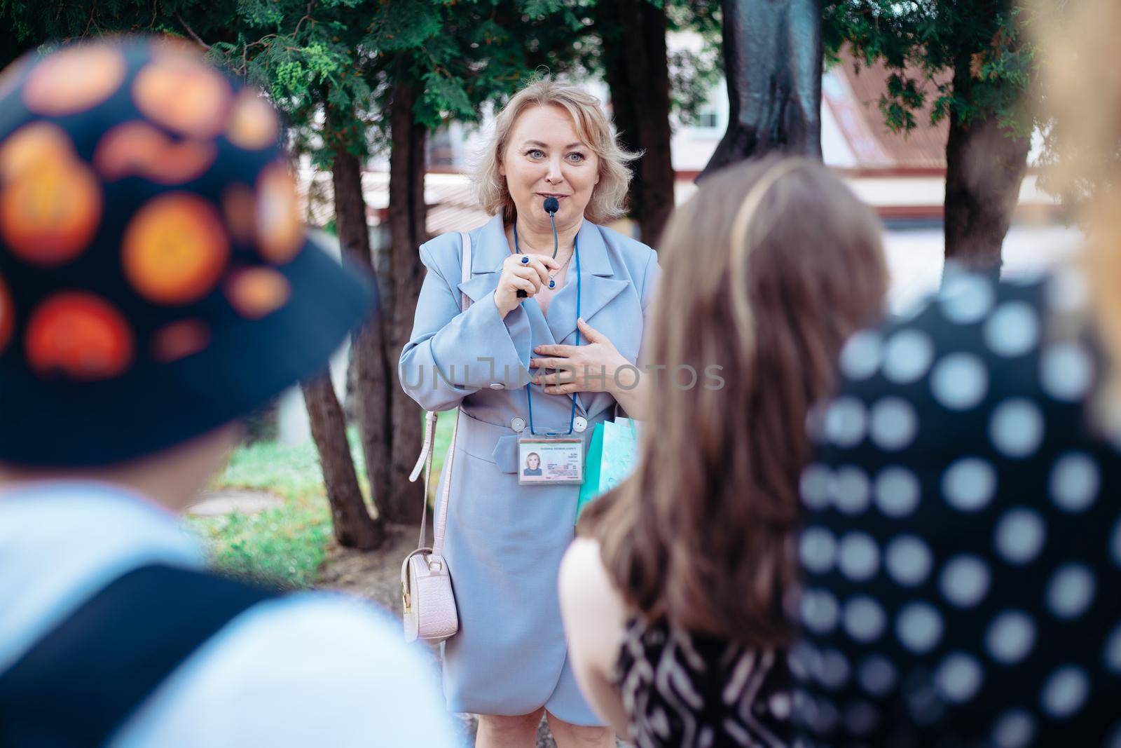 female guide is telling a group of tourists about something. by SmartPhotoLab