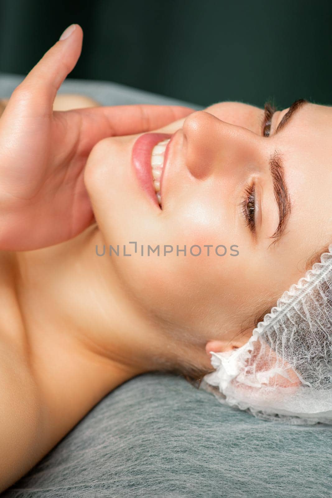 Doctor examining the beautiful face of young smiling woman in beauty clinic