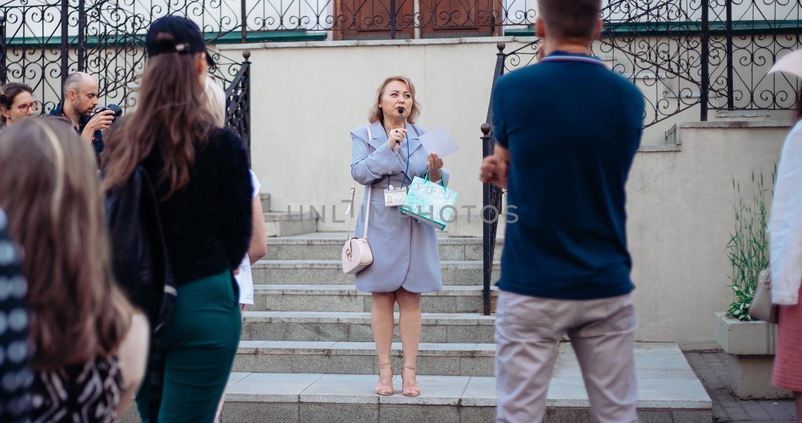 female guide and a group of tourists standing on the steps of the hotel.