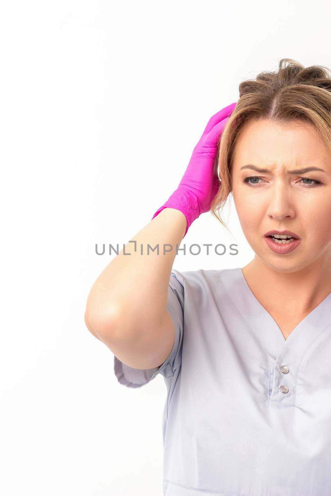 The emotionally shocked young female medical worker holding hands on her head fell into panic on white background, infection, epidemic, virus, and disease concept