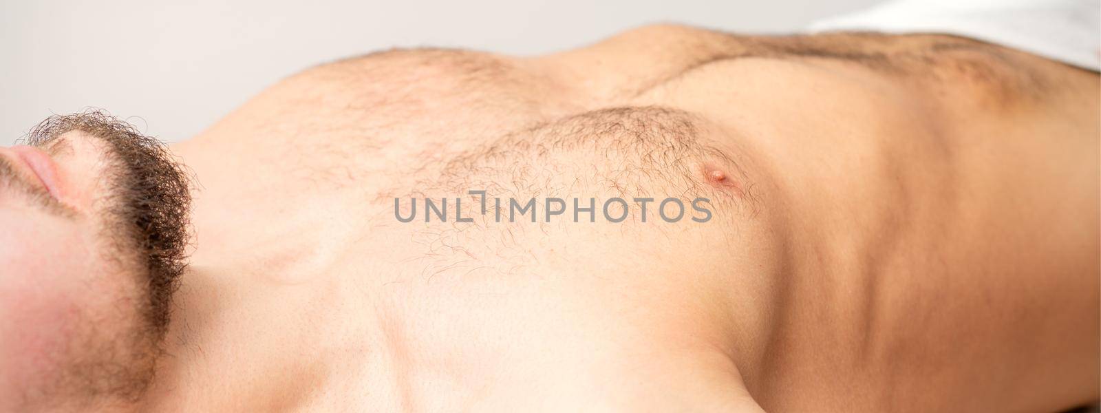 Hairy body, stomach, and chest of a man lying before epilation. by okskukuruza