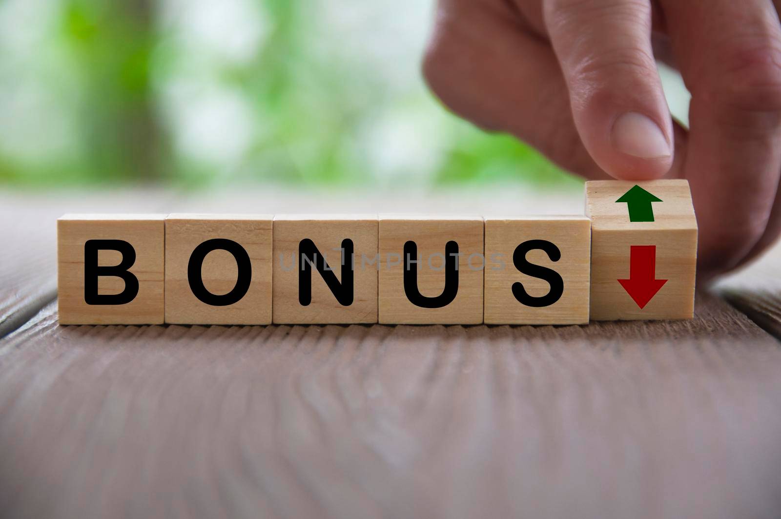 Finger turning wooden block changing the arrow direction up and down for bonus. Salary and bonus increment concept.