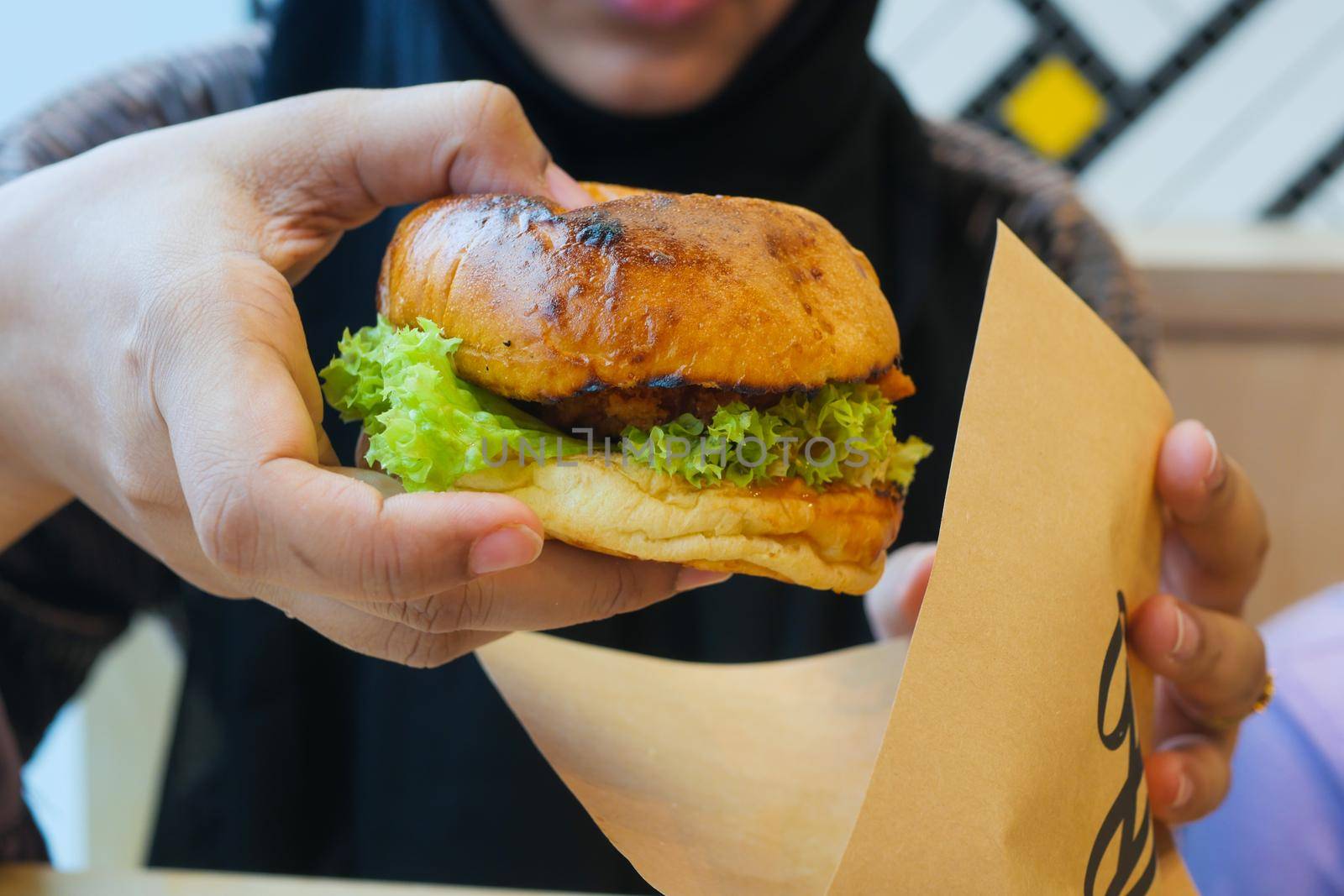 hand holding beef burger on table close up .