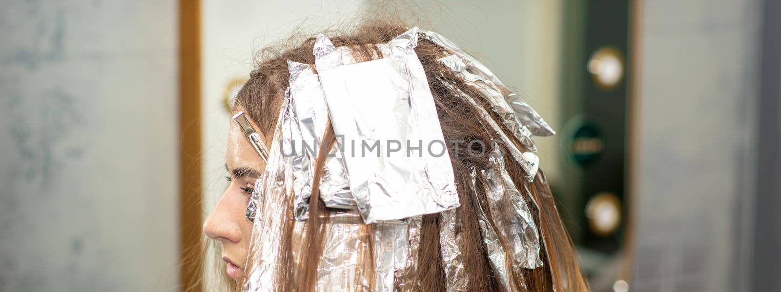 Hair foiled during hair dyeing of a young woman in hair salon close up