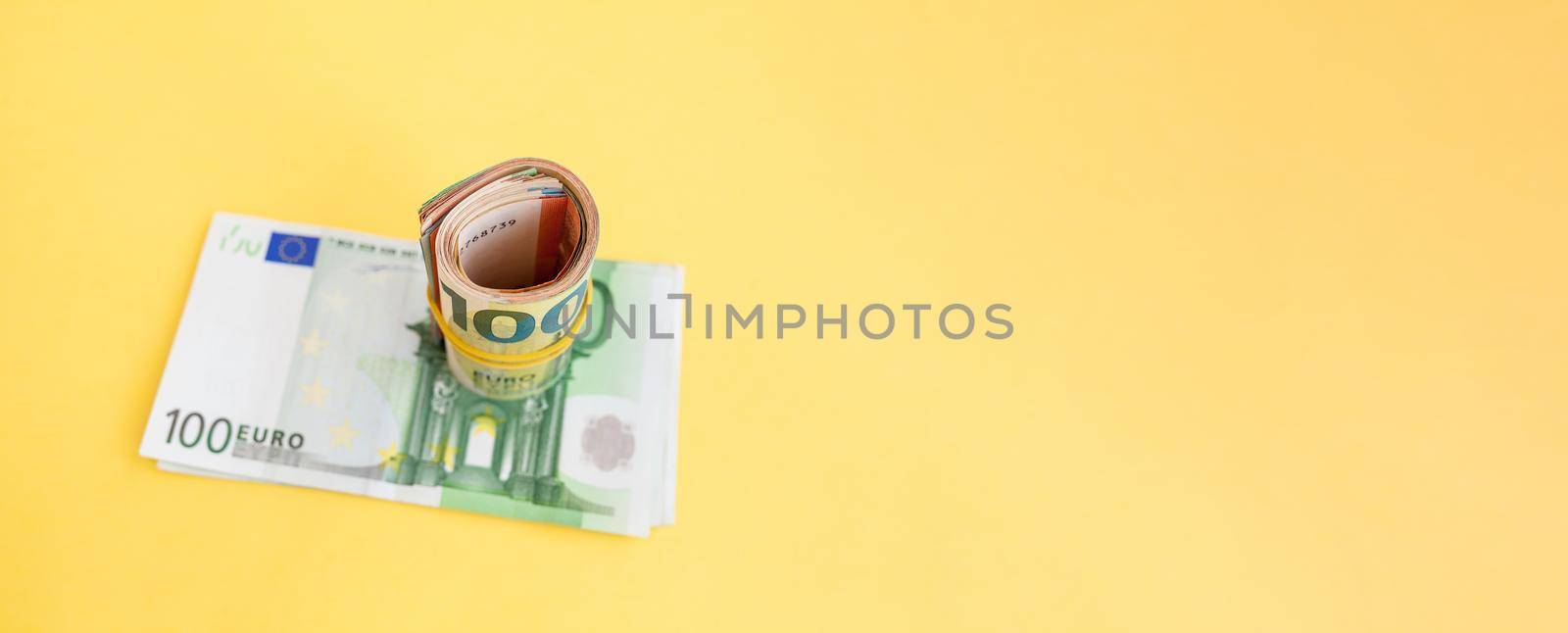 Money roll euro banknotes with yellow rubber band on yellow background by AnatoliiFoto