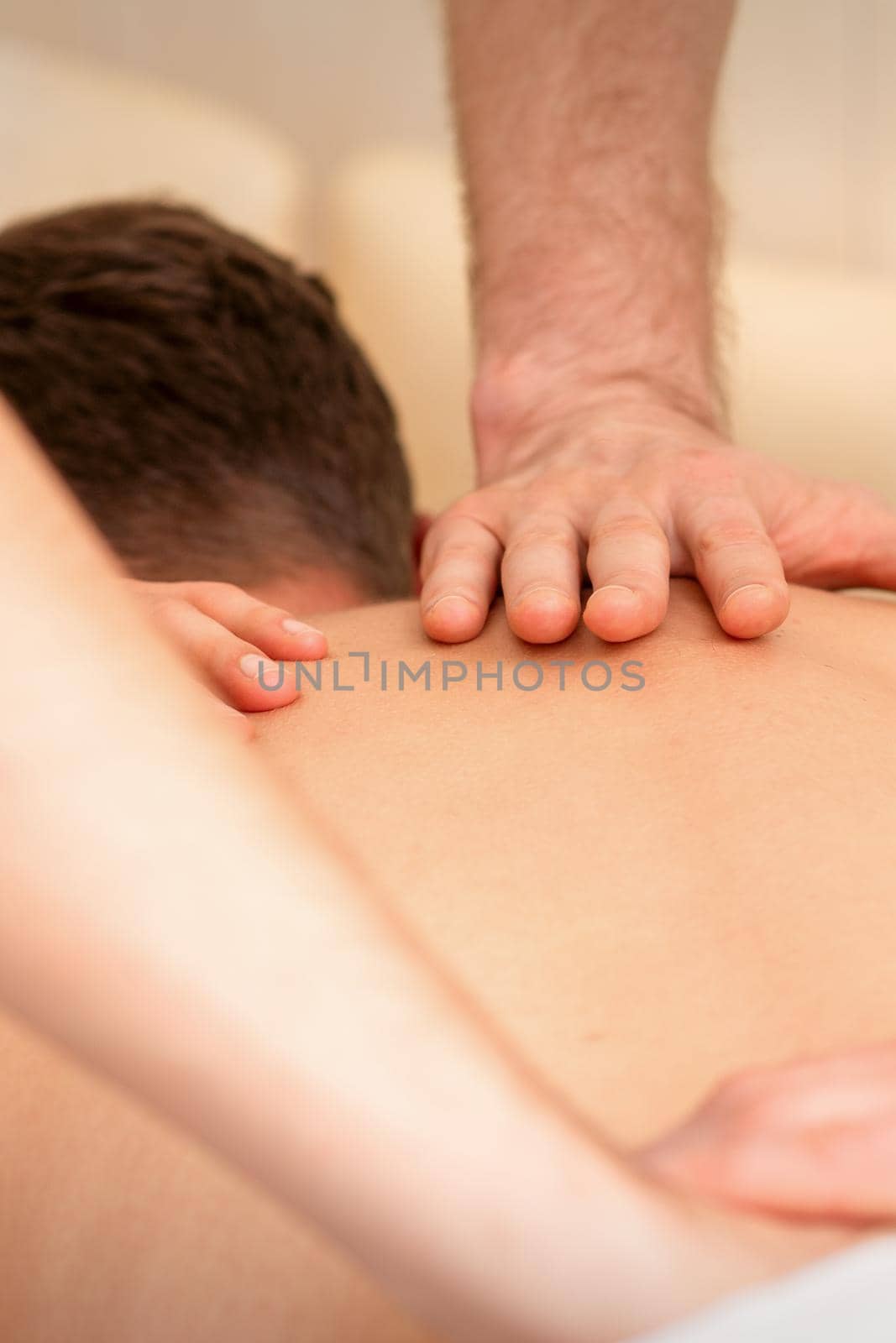 Young man receiving back massage in four hands in spa beauty salon. by okskukuruza
