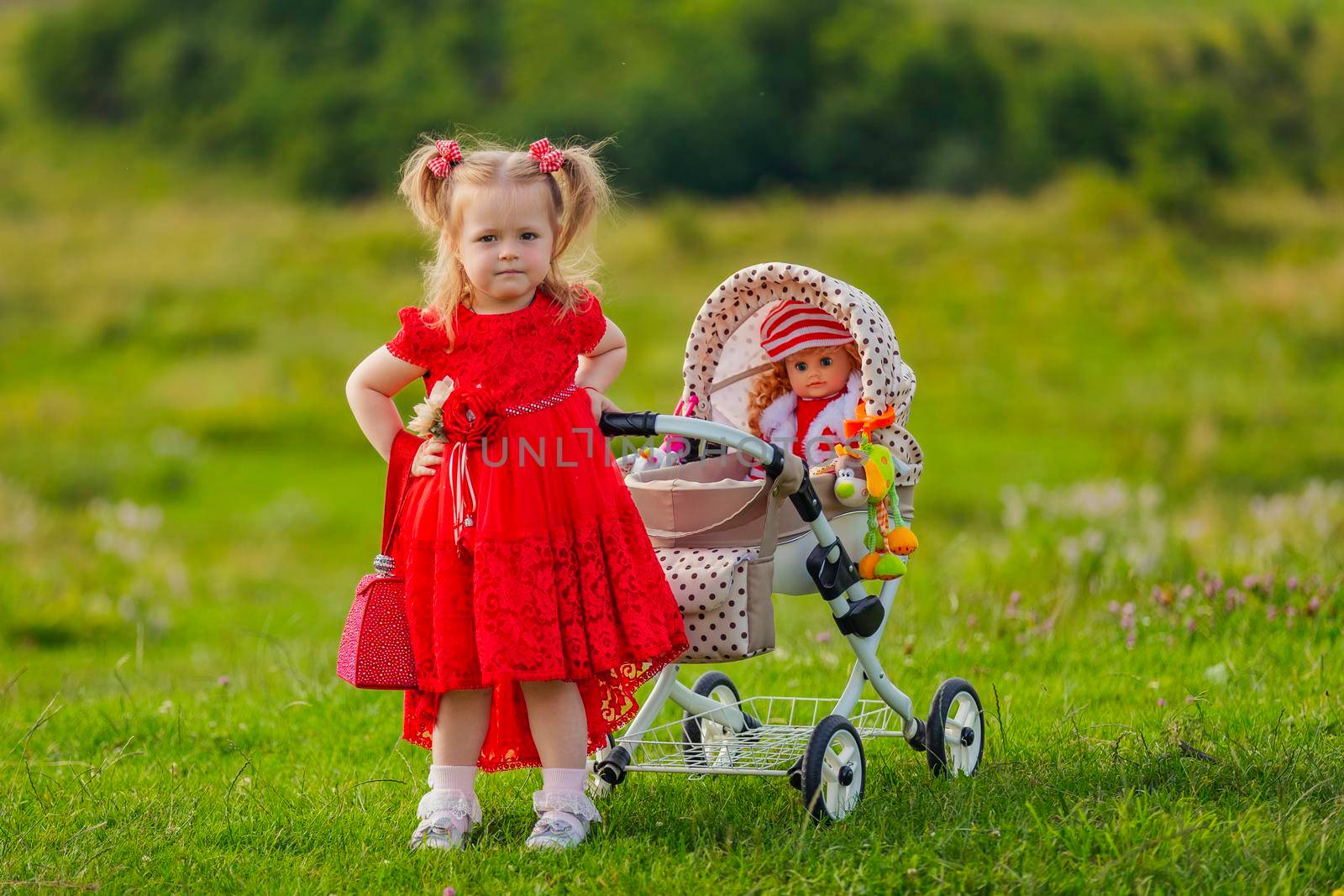 girl playing with a doll in a stroller in nature