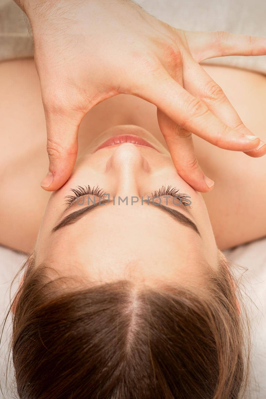 Face massage with fingers of a masseur. Female facial skin care at a beauty spa salon. by okskukuruza