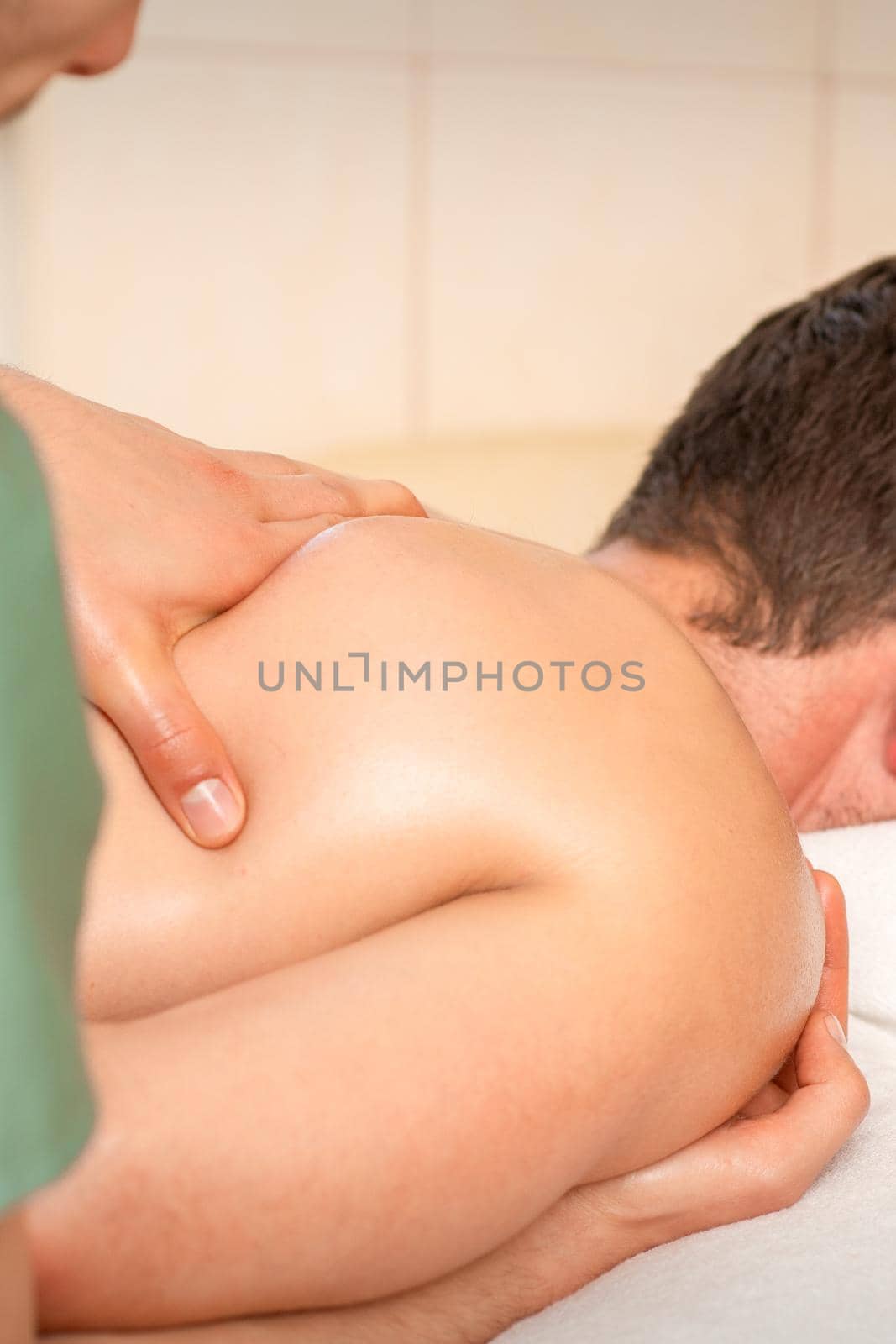 Physiotherapist giving shoulder massage to man in hospital