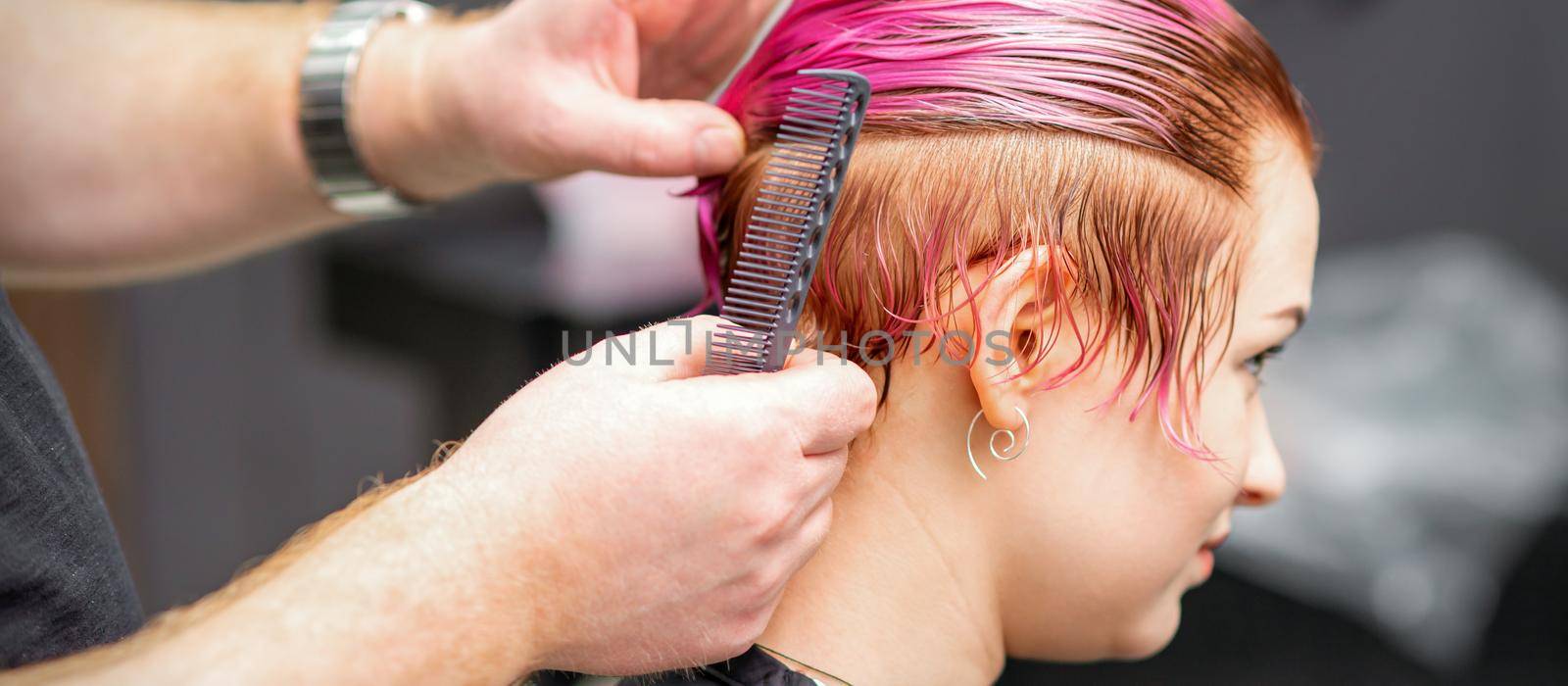 Styling female hair. Male hairdresser makes hairstyle for a young woman in a beauty salon