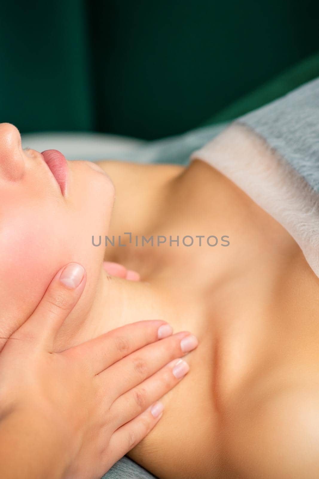 Massaging female neck. Young caucasian woman receiving neck massage relaxing in spa salon. by okskukuruza