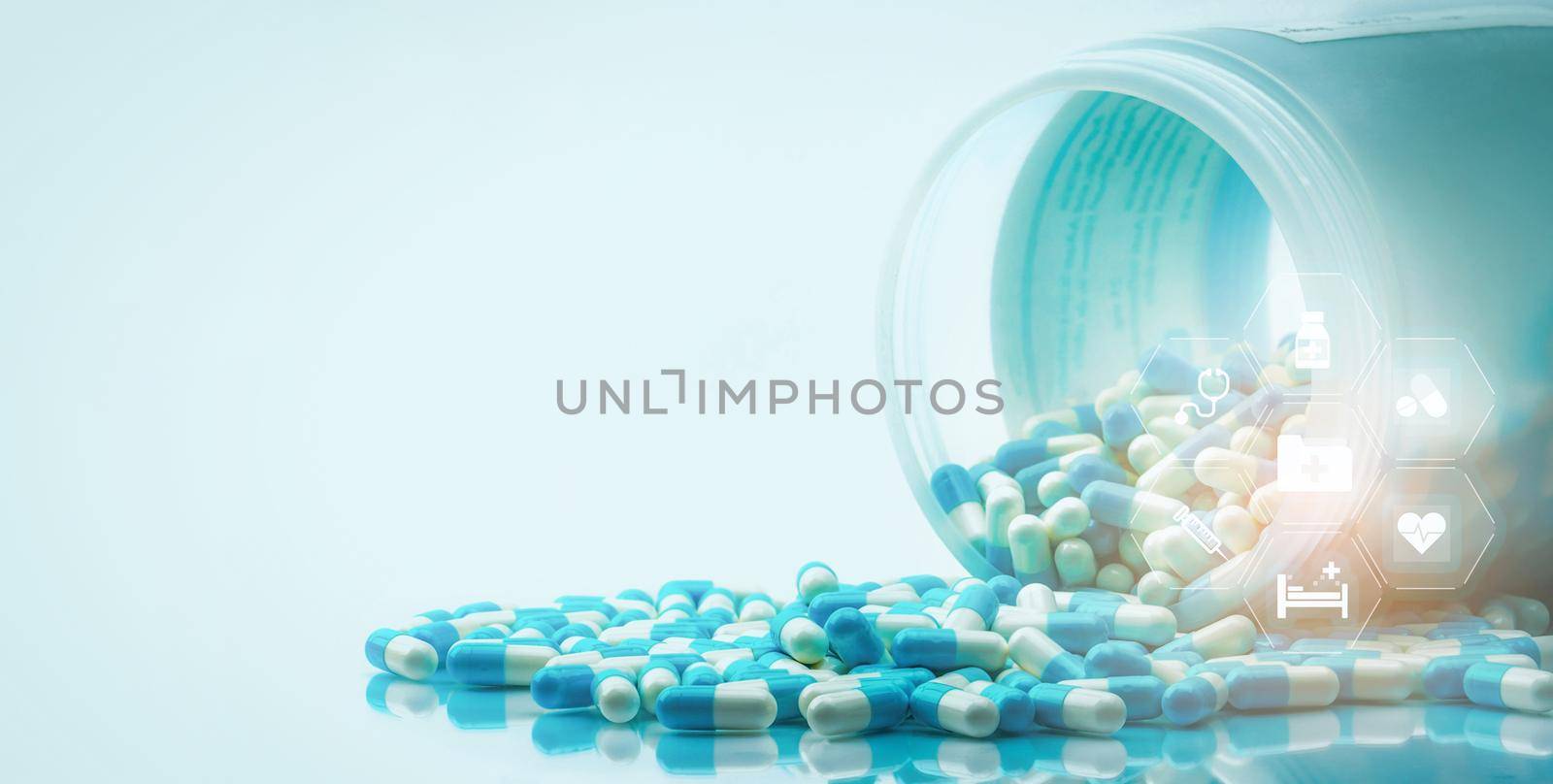 Blue and white capsules pills spilled out of white plastic bottle with medical and healthcare icon. Medical and healthcare concept. Hospital care and health insurance service. Hospital care budget. by Fahroni