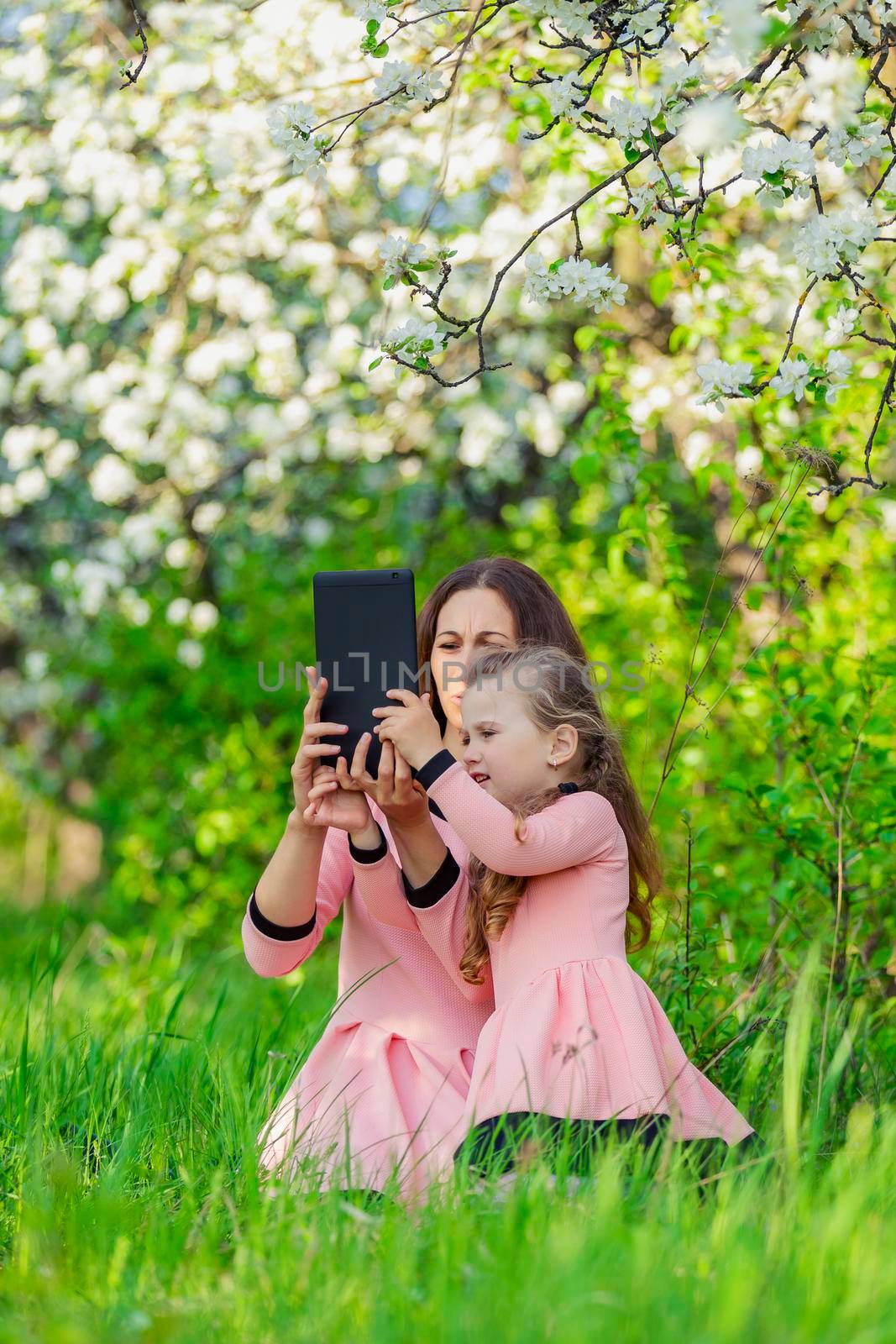 mother and daughter take pictures using a tablet in nature