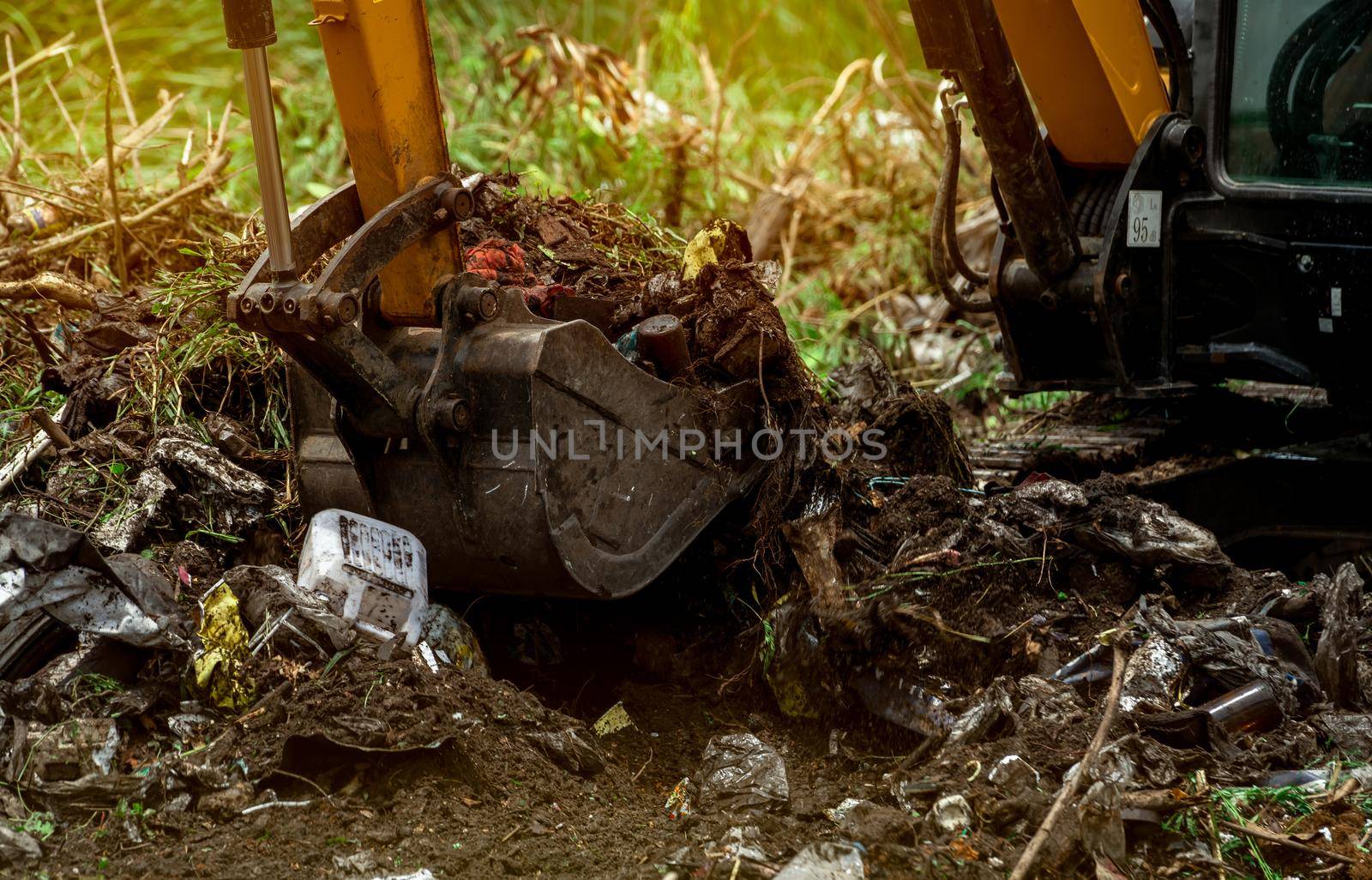 Backhoe digging soil at construction site. Bucket of backhoe digging soil. Clearing and grubbing. Digger working at road construction site. Earth moving machine. Excavation vehicle. Land development. by Fahroni