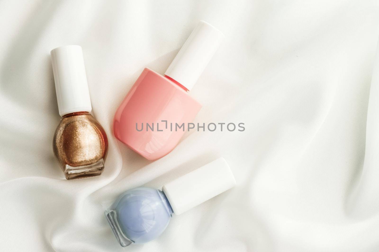 Cosmetic branding, salon and glamour concept - Nail polish bottles on silk background, french manicure products and nailpolish make-up cosmetics for luxury beauty brand and holiday flatlay art design