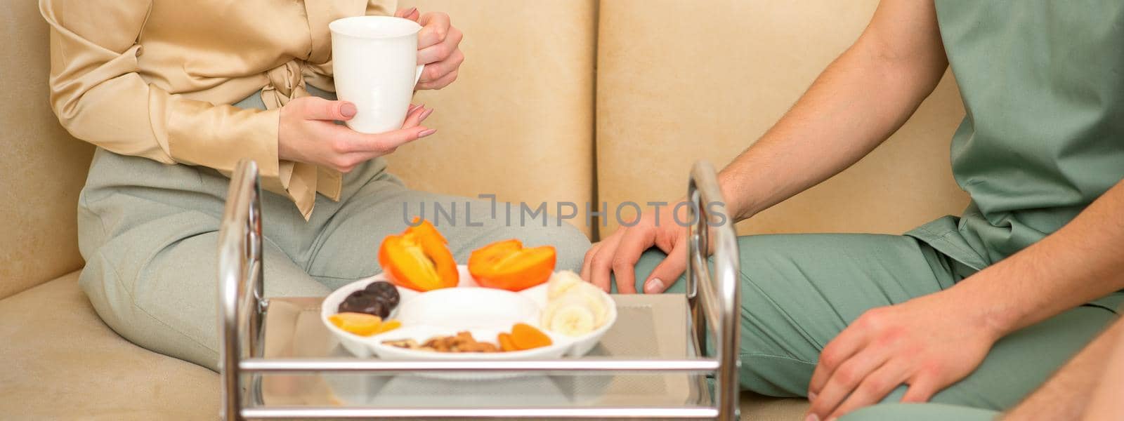 Young caucasian woman consulting with two masseurs during tea with dried fruit in the massage spa