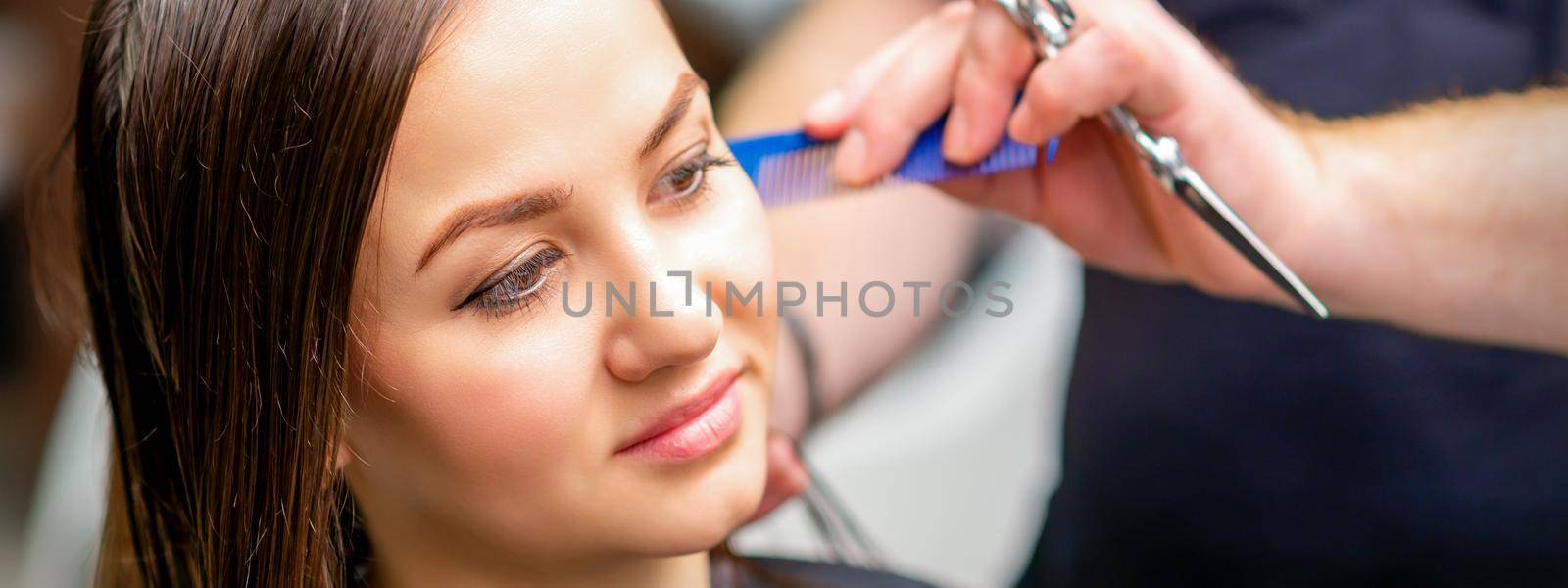 Styling female hair. Male hairdresser makes hairstyle for a young woman in a beauty salon