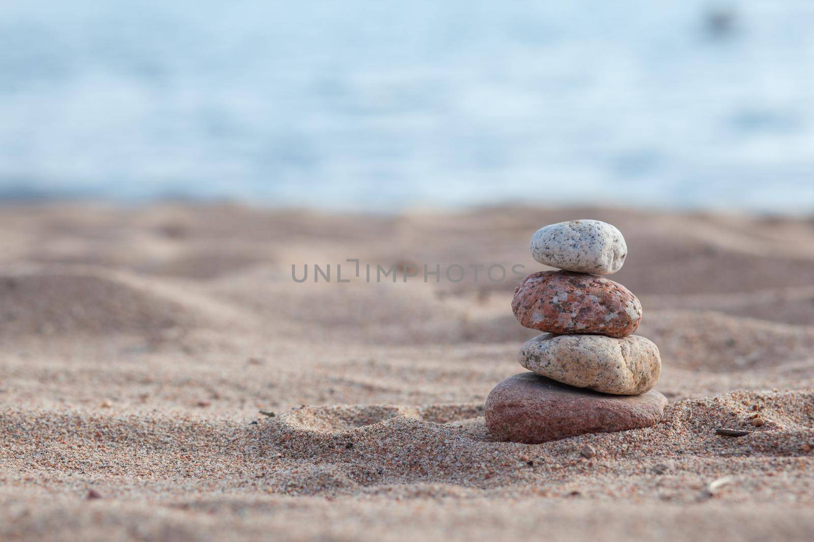 Round stones lie on top of each other in a column on the seashore by AnatoliiFoto