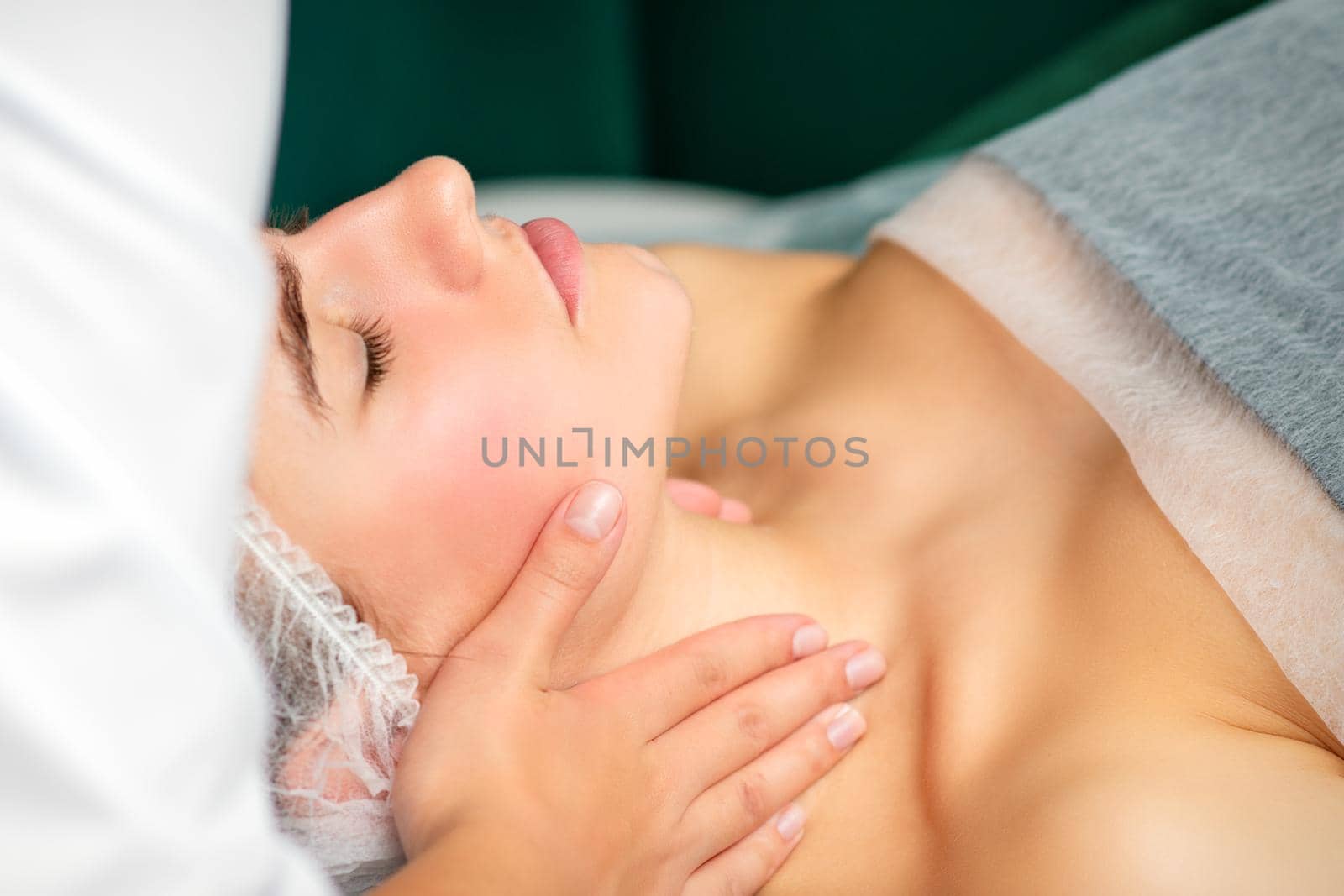 Massaging female neck. Young caucasian woman receiving neck massage relaxing in spa salon