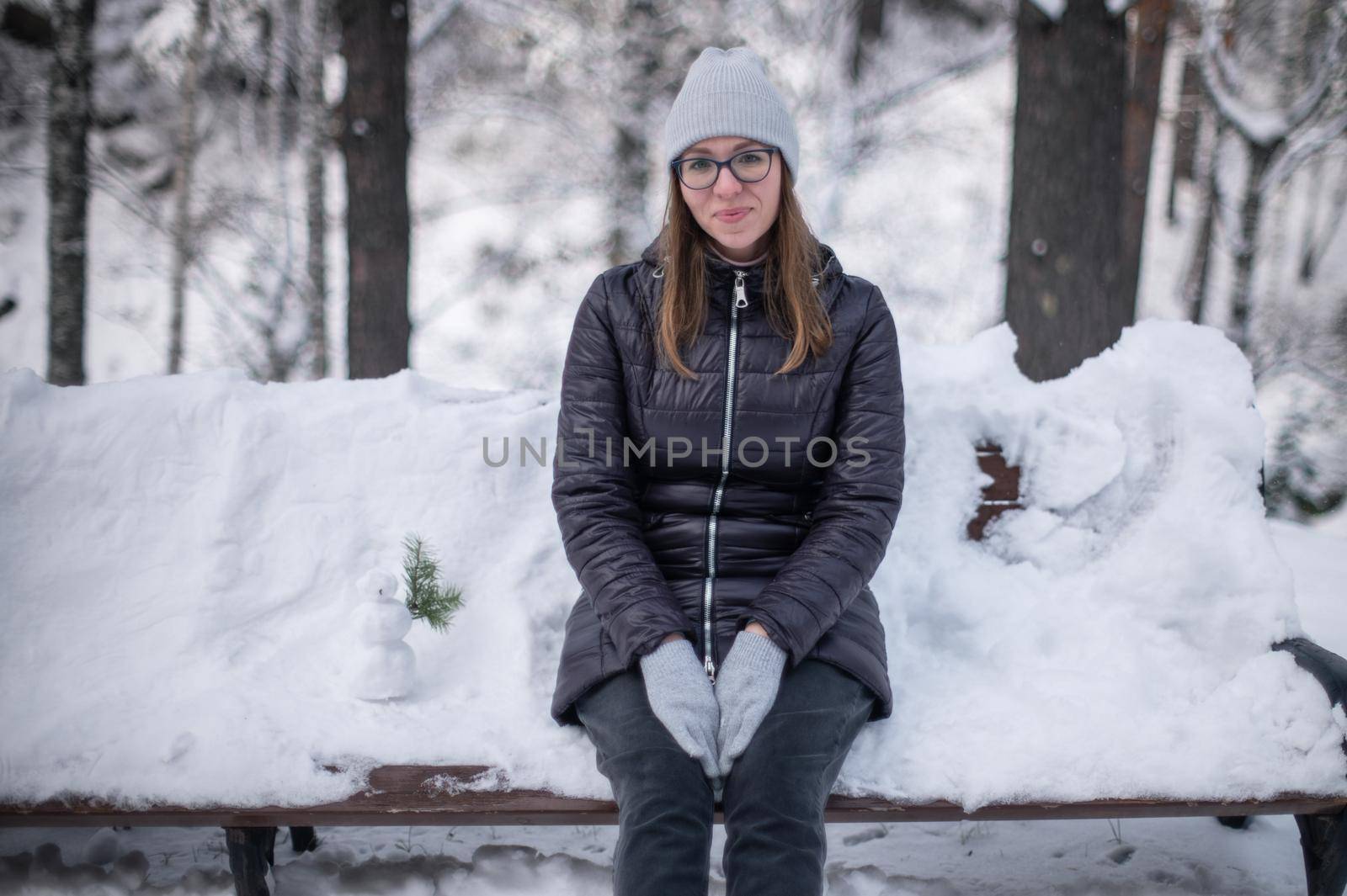 Woman in winter jacket walking in snowy winter forest, snowy winter day