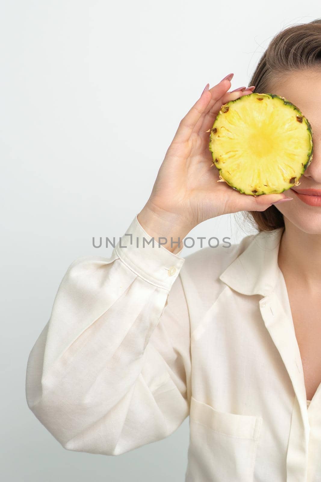 Attractive pretty nice young caucasian woman hold sliced pineapple covering her eye isolated on white color background. by okskukuruza