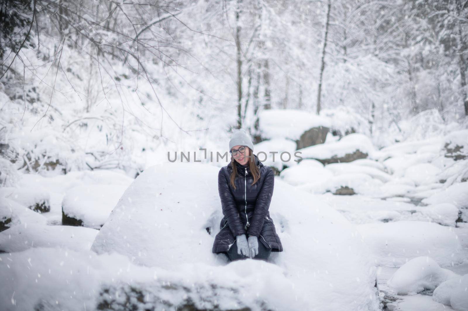 Woman in winter jacket walking in snowy winter forest, snowy winter day