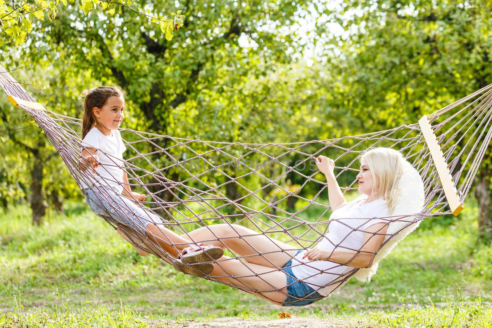 Mother And Daughter Sleeping In Garden Hammock Together