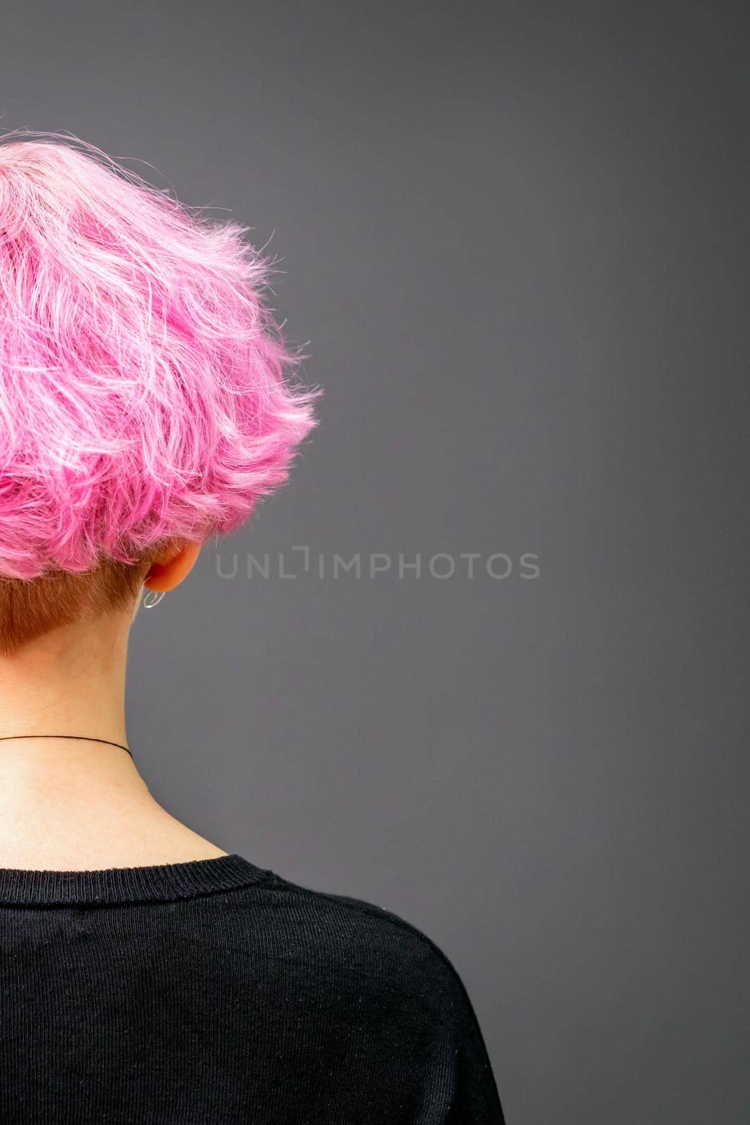 Back of female head with curly short pink hair against the dark background. by okskukuruza