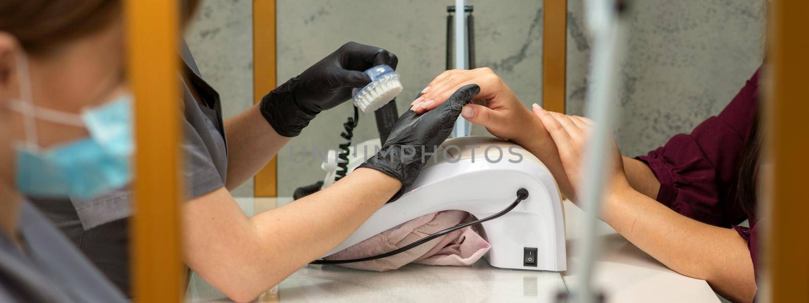 Two women getting a manicure treatment in beauty salon. by okskukuruza