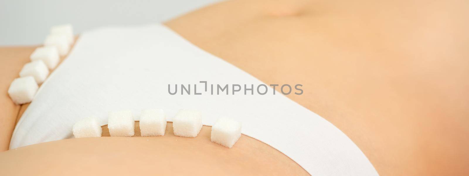 Sugar cubes lying in a row on female bikini zone, the concept of intimate depilation, problems of intimate hygiene