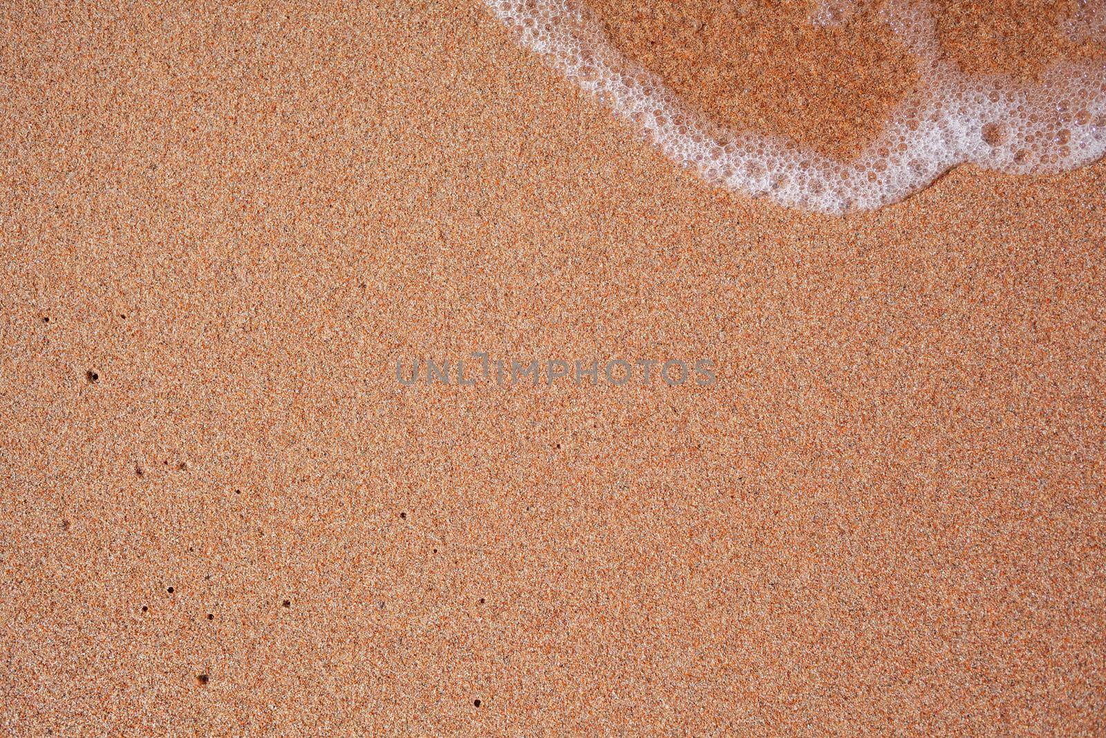 A soft wave runs on a sandy shore on a summer day. Empty space can be used as background for display or montage your top view products.